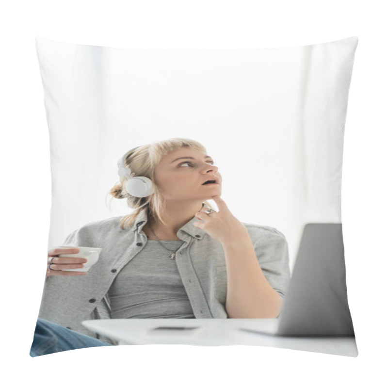 Personality  Pensive Young Woman With Blonde Hair, Bangs And Tattoo On Hand Sitting In Wireless Headphones And Holding Cup Of Coffee Near Laptop And Blurred Smartphone On Table. Freelance. Work From Home Pillow Covers