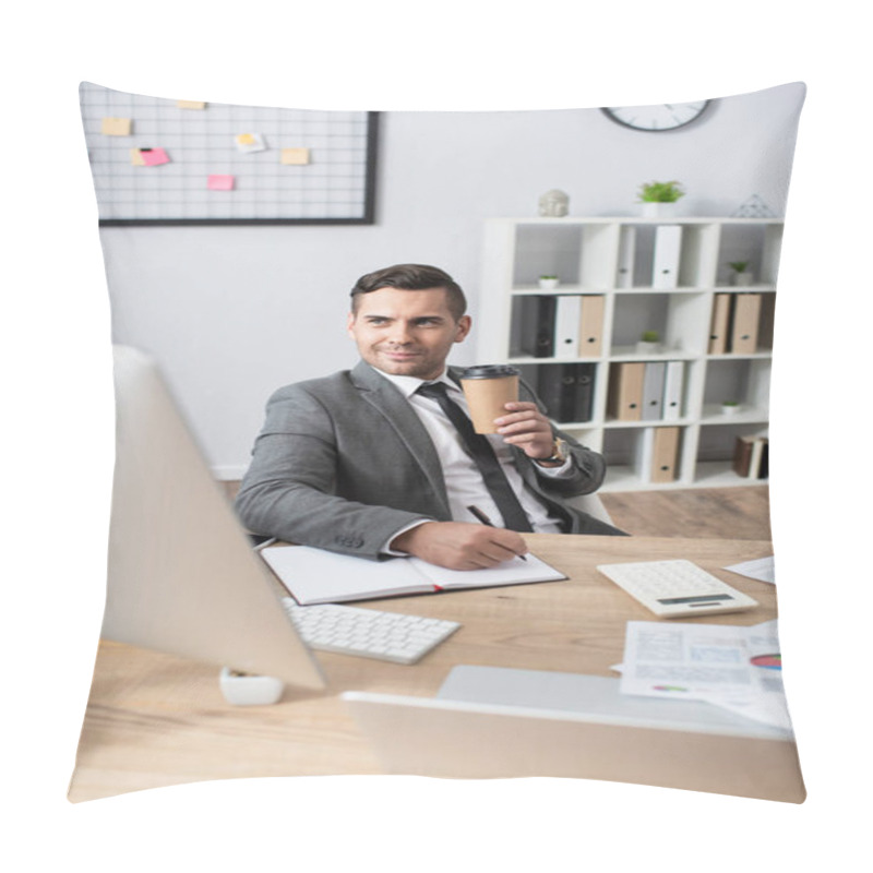 Personality  Smiling Trader Holding Coffee To Go While Writing In Notebook Near Computer Monitor On Blurred Foreground Pillow Covers