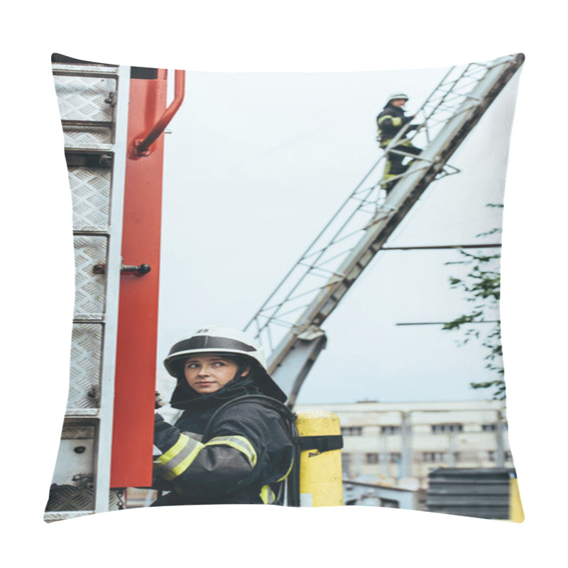 Personality  Female Firefighter In Uniform And Helmet Looking Away While Colleague Standing On Ladder On Street Pillow Covers