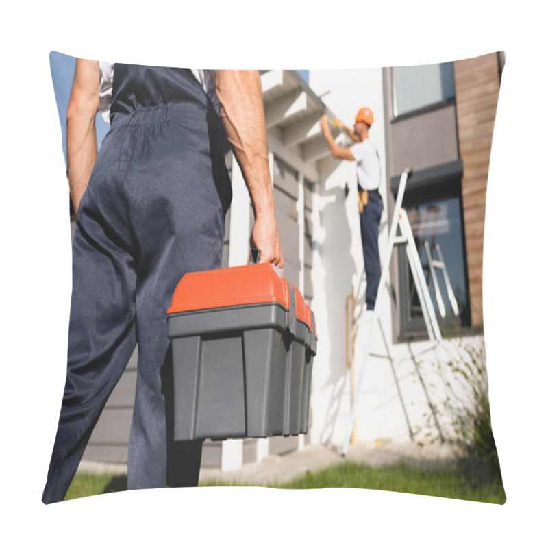 Personality  Selective Focus Of Builder Holding Toolbox While Colleague Working Near House At Background  Pillow Covers