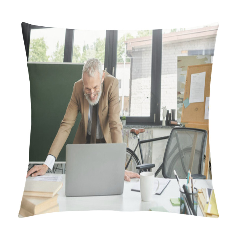 Personality  A Middle-aged Teacher With A Beard Smiles As He Teaches Online, Leaning Over A Laptop On A Table Filled With Books And Office Supplies. Pillow Covers