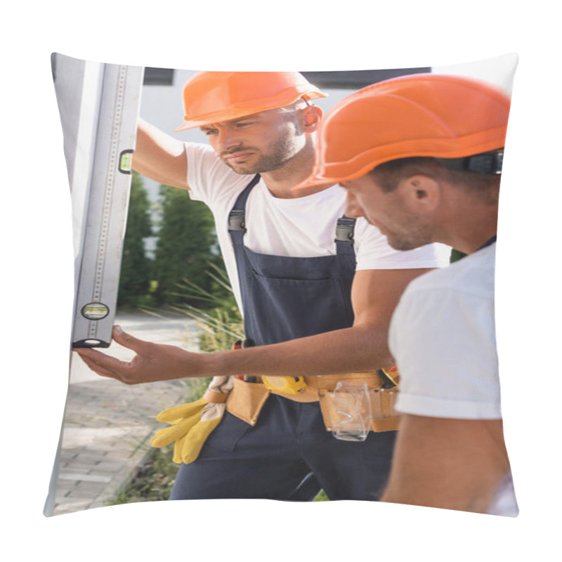 Personality  Selective Focus Of Concentrated Builder Using Spirit Level Near Colleague On Facade Of House  Pillow Covers