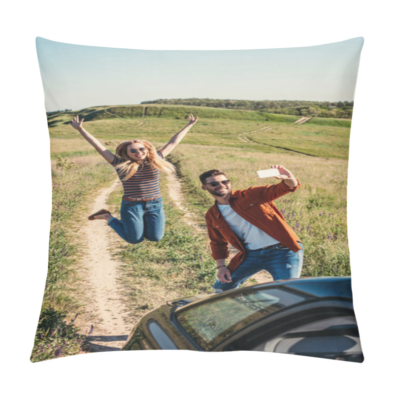 Personality  Smiling Young Woman Jumping With Wide Arms While Her Boyfriend Taking Selfie On Smartphone Near Car On Rural Meadow  Pillow Covers