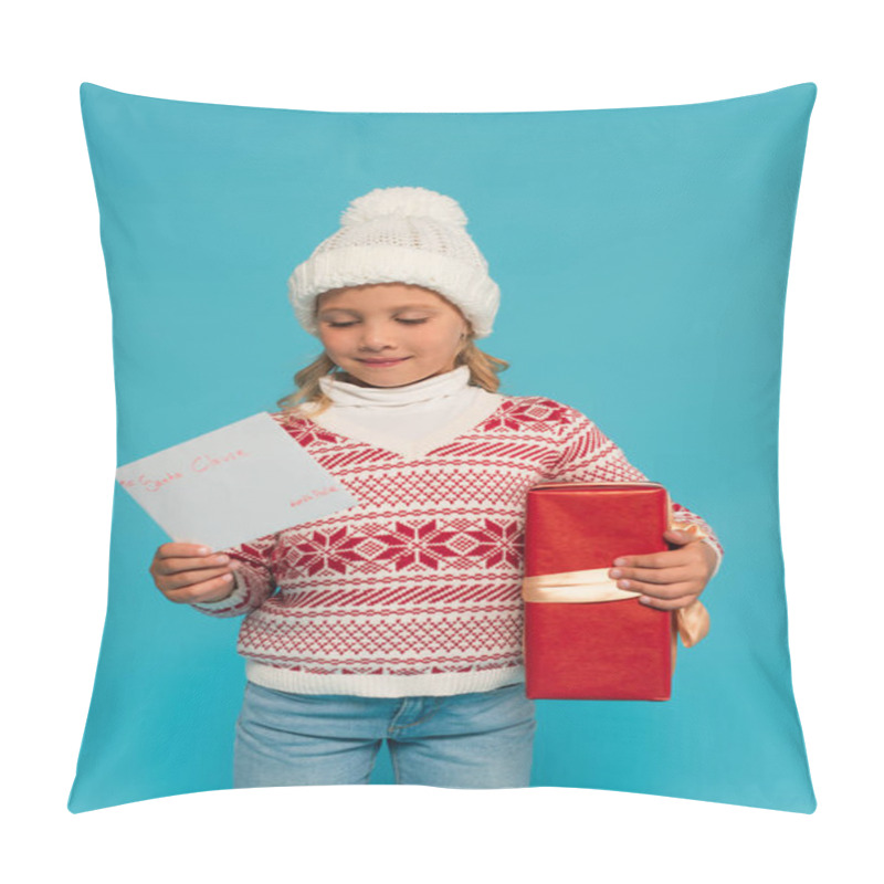 Personality  Pleased Child In Warm Sweater And Hat Holding Present And Letter To Santa Clause Isolated On Blue Pillow Covers