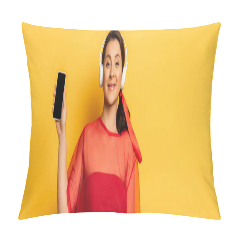 Personality  Horizontal Image Of Woman In Wireless Headphones Showing Smartphone With Blank Screen On Yellow Pillow Covers