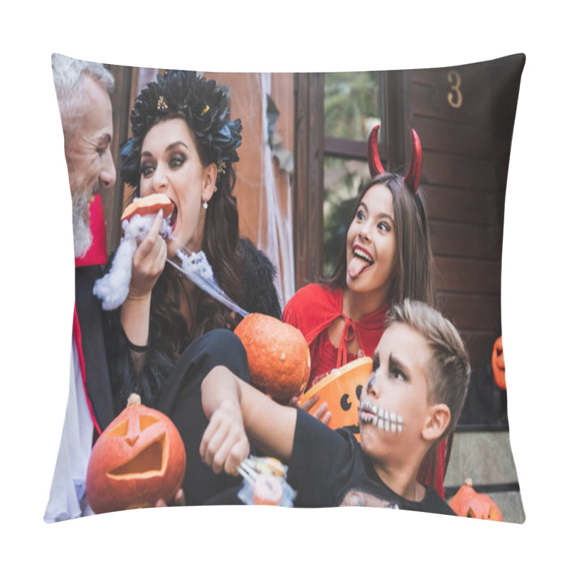 Personality  woman eating raw pumpkin near excited family in spooky halloween costumes pillow covers