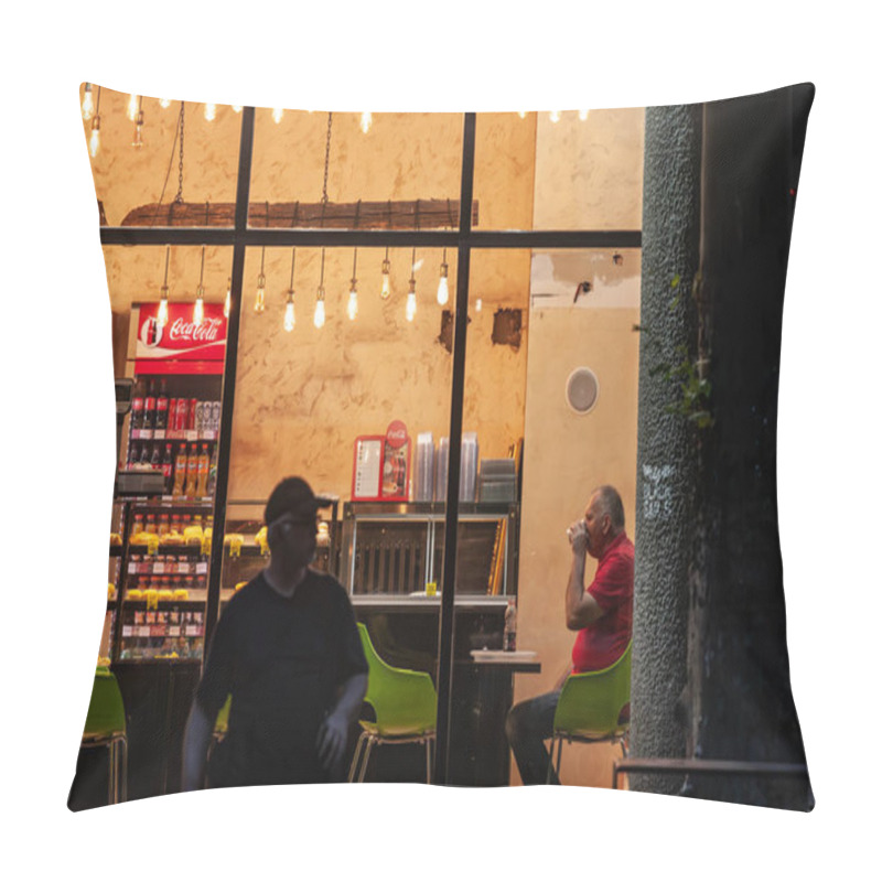 Personality  BELGRADE, SERBIA - OCTOBER 12, 2024: A Man Enjoys A Coffee In A Belgrade Cafeteria At Night, Framed By Warm Interior Lights And Stocked Refrigerators. Pillow Covers