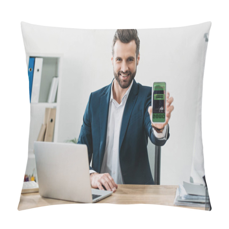 Personality  Businessman Sitting At Table With Laptop And Showing Smartphone With Booking App On Screen In Office Pillow Covers