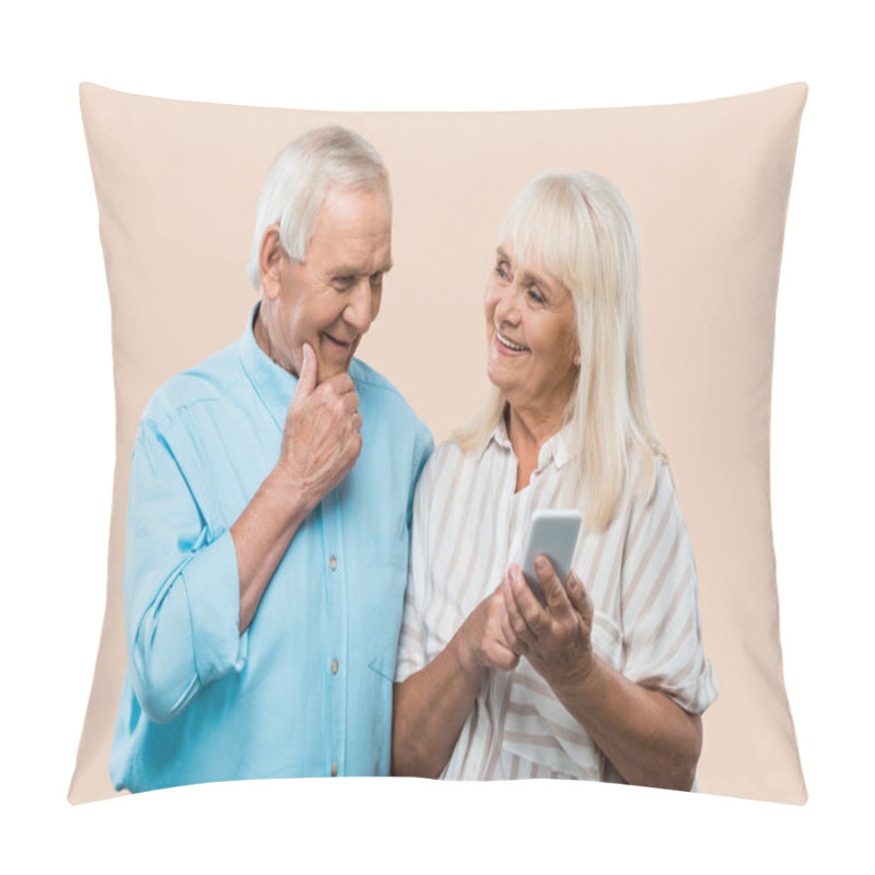 Personality  Cheerful Retired Woman Holding Smartphone And Looking At Husband Isolated On Beige  Pillow Covers