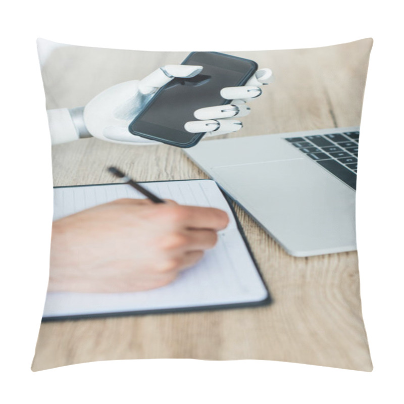 Personality  Close-up View Of Robotic Arm Holding Smartphone And Human Hand Taking Notes At Wooden Table Pillow Covers