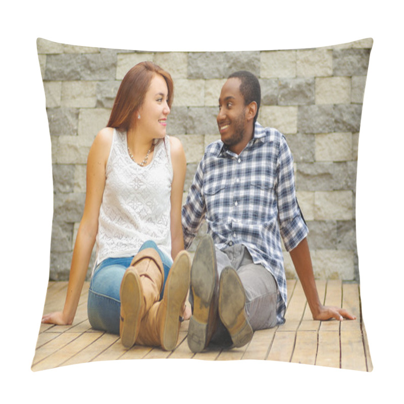 Personality  Interracial Charming Couple Wearing Casual Clothes Sitting On Wooden Surface Posing For Camera Staring At Each Other, Grey Brick Wall Background Pillow Covers