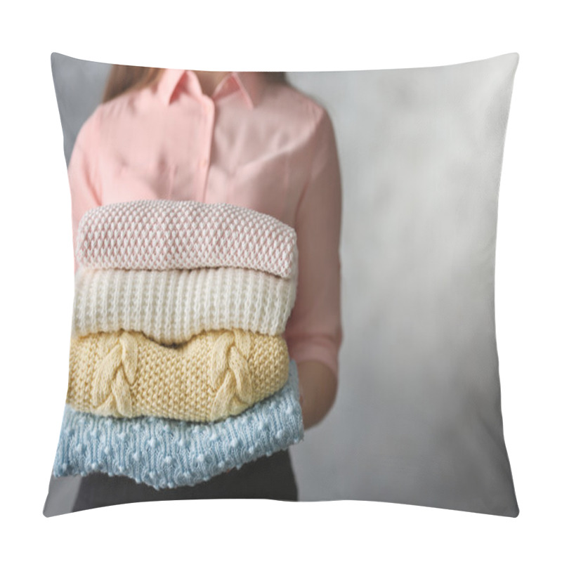 Personality  Stack Of Knitted Clothes In Female Hands On Grey Blurred Background Pillow Covers