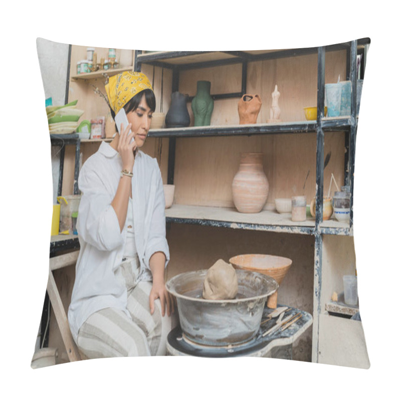 Personality  Young Asian Female Potter In Workwear And Headscarf Talking On Smartphone While Sitting Near Clay On Pottery Wheel And Tools And Working In Pottery Studio, Artisan Crafting Ceramics In Studio Pillow Covers