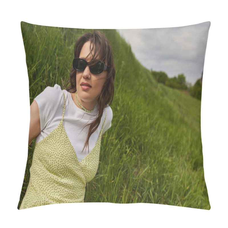 Personality  Portrait Of Trendy Brunette Woman In Sunglasses And Stylish Sundress Sitting On Hill With Blurred Green Grass And Cloudy Sky At Background, Natural Landscape Concept Pillow Covers