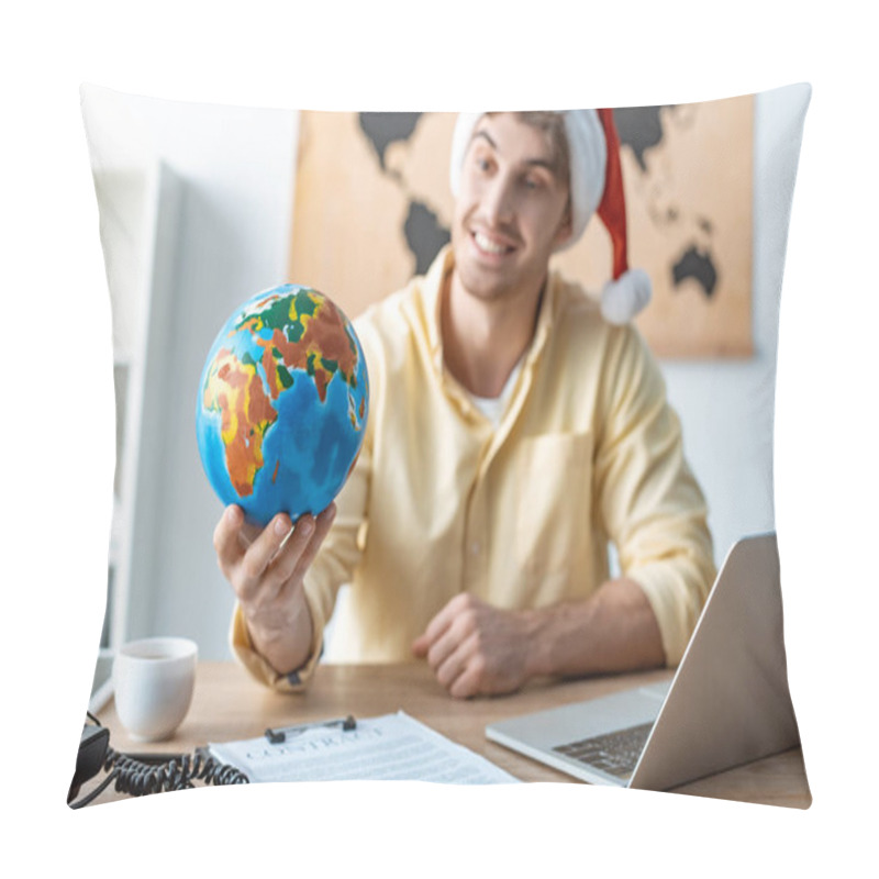 Personality  Selective Focus Of Cheerful Travel Agent In Santa Hat Holding Globe While Sitting At Workplace Pillow Covers