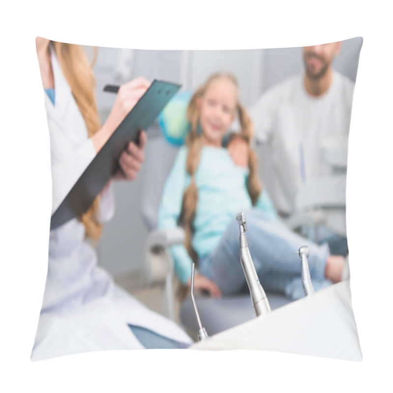 Personality  Cropped Shot Of Female Dentist Writing In Clipboard While Little Child And Her Young Father Sitting On Background Pillow Covers