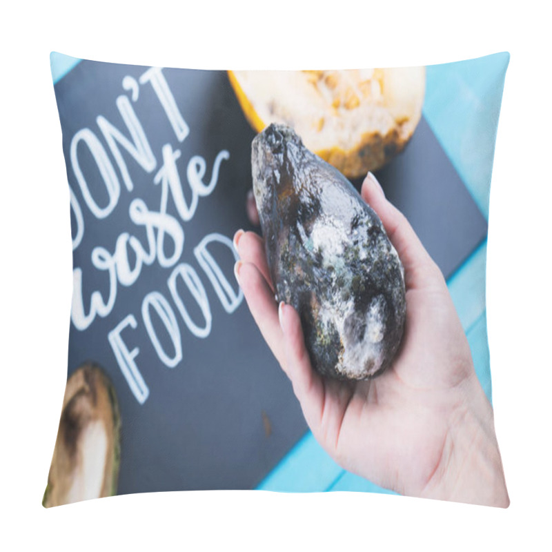 Personality  Close Up Of Female Hand Holding A Moldy Avocado On A Chalkboard With Dont Waste Food Lettering And Rotten Fruits. Selective Focus Pillow Covers