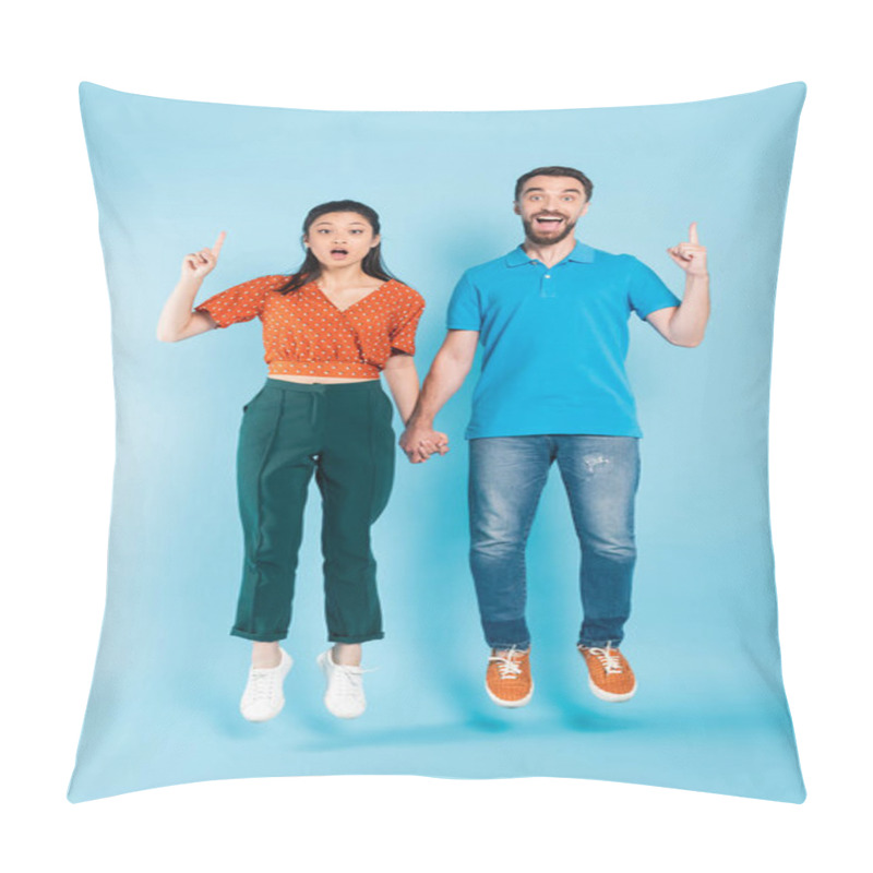 Personality  Excited Asian Couple Holding Hands And Showing Idea Gesture While Levitating On Blue Pillow Covers