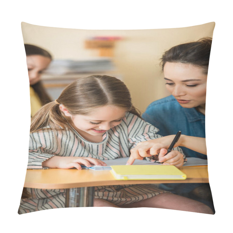 Personality  Young Teacher Pointing Near Smiling Kid Writing In Notebook And Asian Girl On Blurred Background Pillow Covers