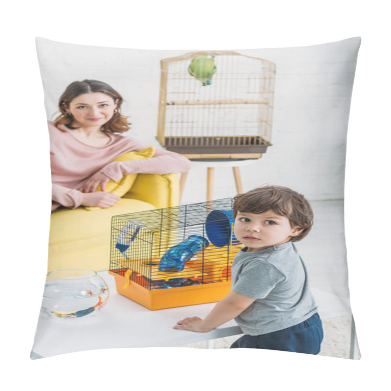 Personality  Selective Focus Of Cute Child Standing Near Table With Fish Bowl And Pet Cage, And Smiling Mother Resting On Yellow Sofa Pillow Covers