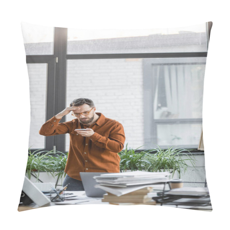 Personality  Worried Businessman In Eyeglasses Looking At Mobile Phone And Holding Hand Near Head Next To Work Desk With Laptop, Notebooks, Folders, Books, Paper Cup And Decorative Plants In Modern Office Pillow Covers