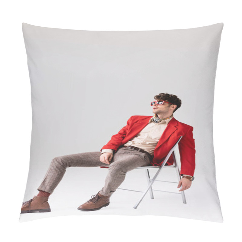 Personality  Stylish man in red blazer leaning back and posing while sitting on chair on grey pillow covers