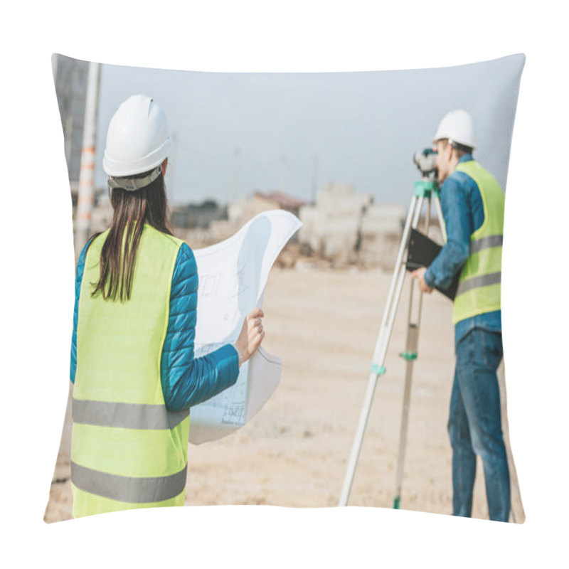 Personality  Selective Focus Of Surveyor With Blueprint And Colleague Using Digital Level On Construction Site Pillow Covers