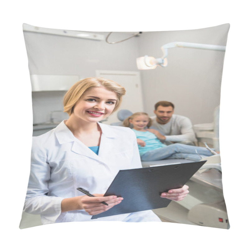 Personality  Young Female Dentist With Clipboard Looking At Camera While Little Child And Her Father Sitting On Background Pillow Covers