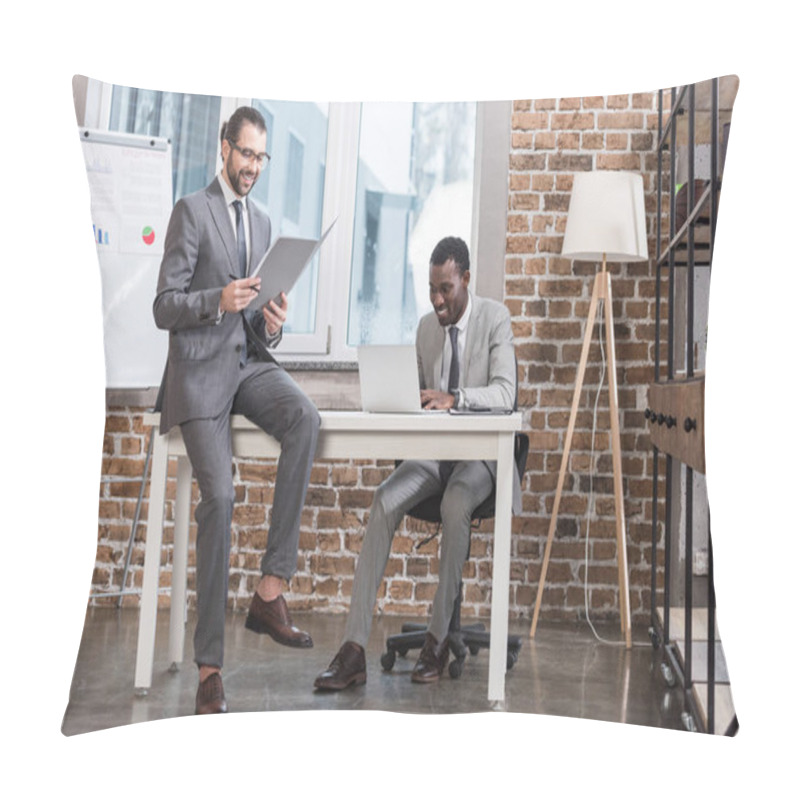 Personality  Smiling Businessman Sitting On Table And Reading Document While African American Partner Working On Laptop In Officeac Pillow Covers