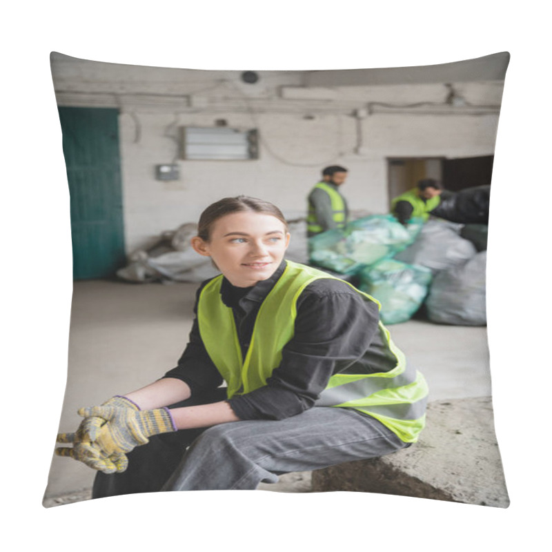 Personality  Positive Young Sorter In High Visibility Vest And Gloves Looking Away While Relaxing Near Blurred Colleagues And Plastic Bags At Background In Garbage Sorting Center, Recycling Concept Pillow Covers