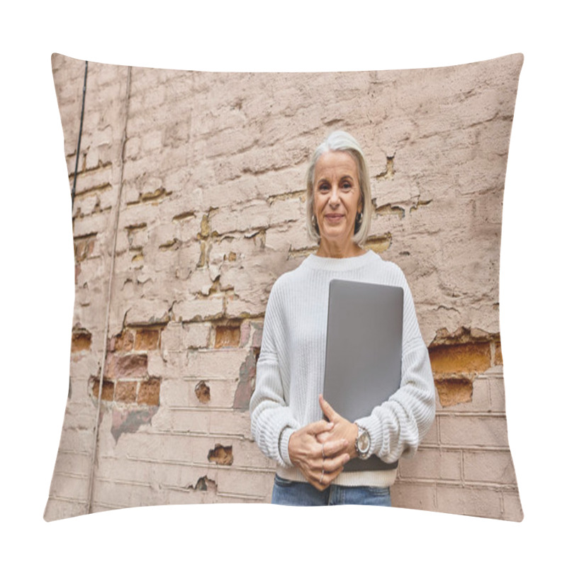 Personality  A Sophisticated Gray Haired Woman Smiles Warmly With Her Laptop Against A Brick Backdrop. Pillow Covers