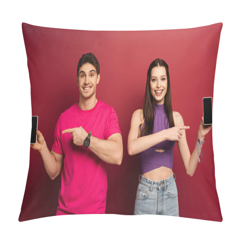 Personality  Beautiful Smiling Couple Pointing At Smartphones With Blank Screens On Red Pillow Covers