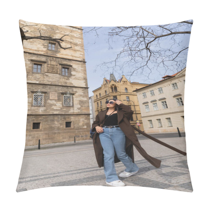 Personality  Stylish young woman in coat and sunglasses walking on urban street in Prague  pillow covers