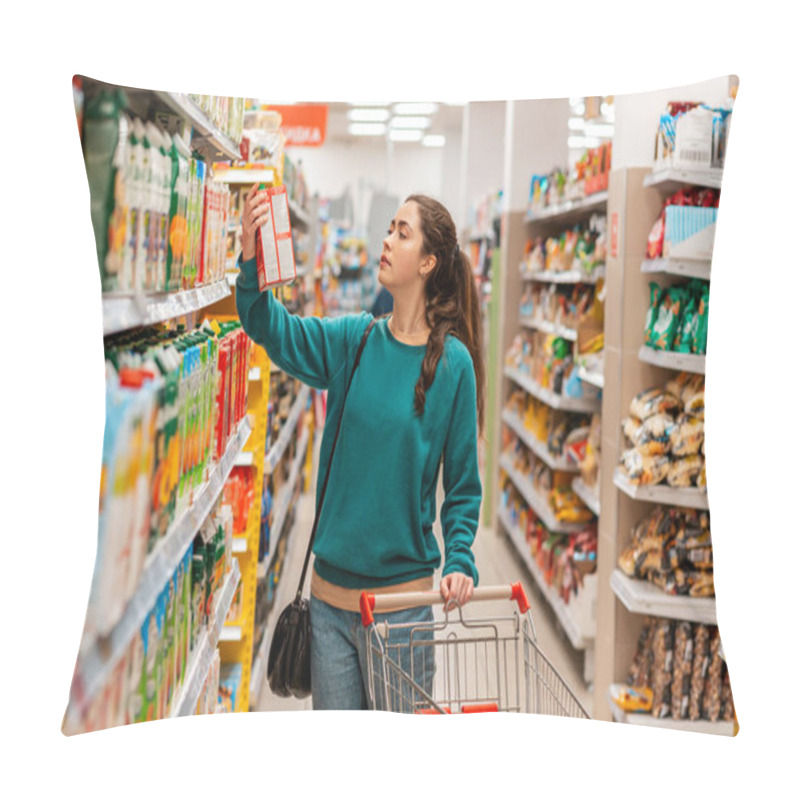 Personality  A Young Caucasian Beautiful Woman With A Grocery Cart, Takes A Box Of Juice From The Top Shelf. Shelves With Goods In A Blur In The Background. The Concept Of Buying Goods And Shopping. Pillow Covers