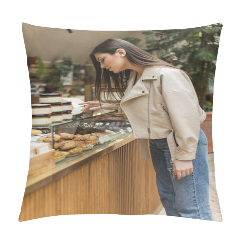 Personality  Brunette Young Woman With Long Hair In Beige Leather Jacket And Denim Jeans Standing Near Cake Display And Choosing Pastry Near Jars Of Jam In Modern Bakery Shop In Istanbul  Pillow Covers