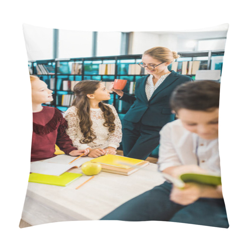 Personality  Smiling Young Female Teacher Holding Cup And Looking At Schoolchildren In Library Pillow Covers