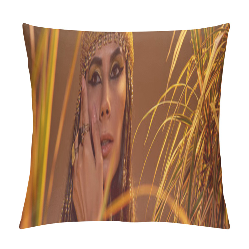 Personality  Woman In Egyptian Headdress Touching Cheek While Standing Near Plants Isolated On Brown, Banner Pillow Covers