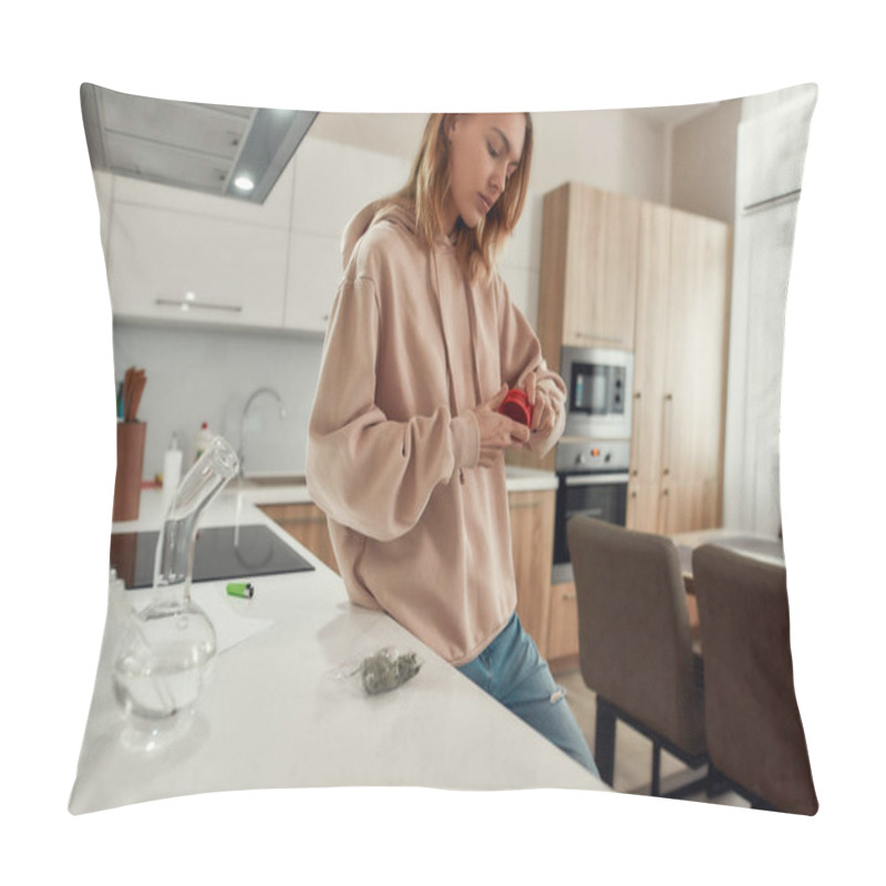 Personality  Preparation. Young Woman Using Red Marijuana Grinder, While Standing In The Kitchen. Glass Water Pipe Or Bong, Cannabis Buds In A Plastic Bag On The Table. Cannabis And Weed Legalization Concept Pillow Covers