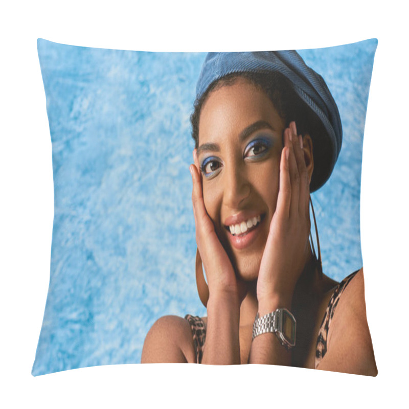 Personality  Portrait Of Trendy Young African American Model With Bold Makeup, Earrings And Beret Touching Cheeks And Smiling At Camera On Blue Textured Background, Stylish Denim Attire Pillow Covers