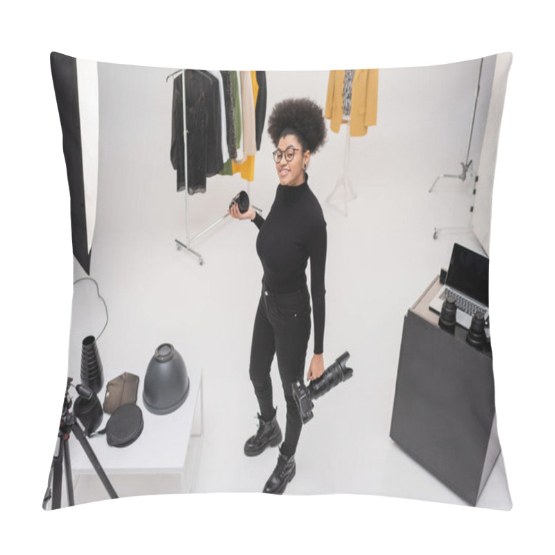 Personality  High Angle View Of Happy African American Photographer Holding Digital Camera And Photo Lens Near Stylish Clothes In Photo Studio Pillow Covers