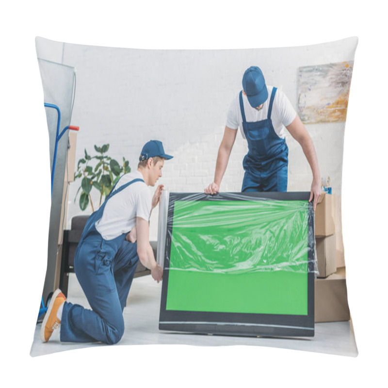 Personality  Two Movers In Uniform Using Roll Of Stretch Film While Wrapping Tv With Green Screen In Apartment Pillow Covers