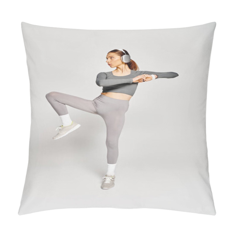 Personality  A Sporty Young Woman In A Gray Top And Grey Pants Elegantly Performs A Kick On A Matching Gray Background. Pillow Covers