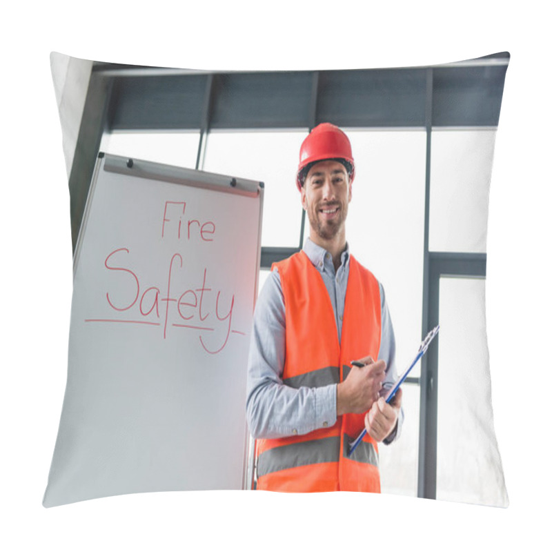 Personality  Cheerful Firefighter In Helmet Holding Clipboard And Pen While Standing Near White Board With Fire Safety Lettering Pillow Covers