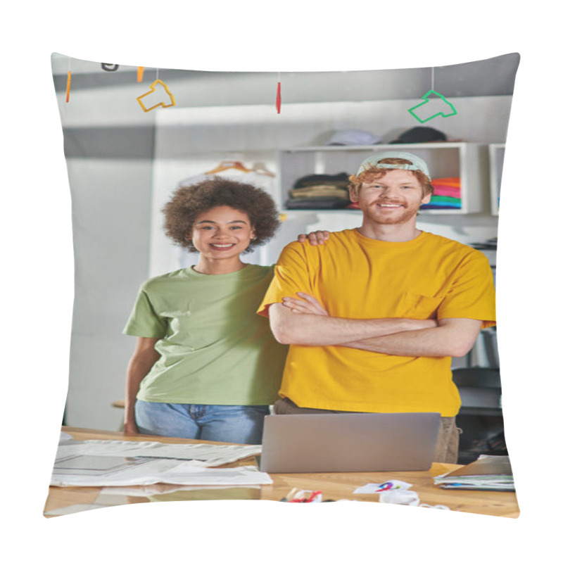 Personality  Smiling Young Multiethnic Designers Looking At Camera And Posing While Standing Near Laptop And Clothes During Project In Blurred Print Studio At Background, Start-up Innovation Concept Pillow Covers