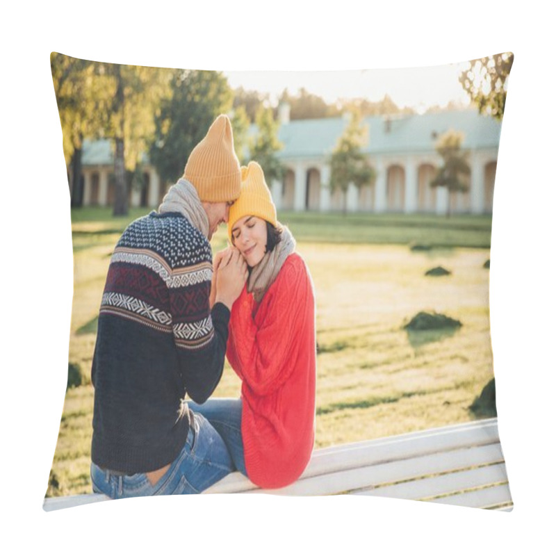 Personality  True Feelings And Romantisism Concept. Adorable Young Woman In Knitted Yellow Hat And Red Warm Sweater Warms Her Hands In Boyfriend`s Hands, Sit Together On Bench, Closes Eyes With Great Enjoyment Pillow Covers