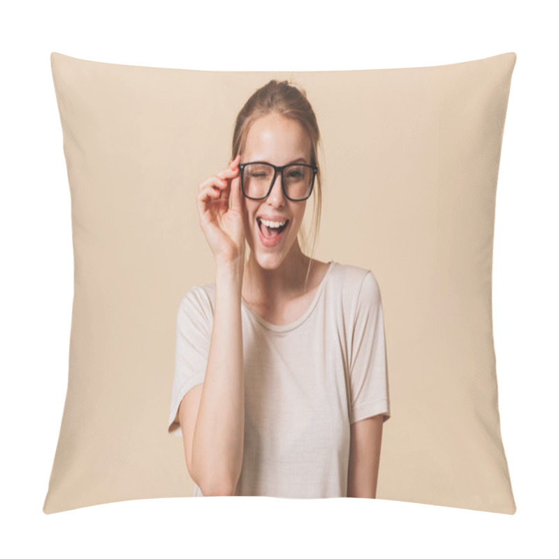 Personality  Portrait Of Beautiful Cheerful Woman 20s Wearing Basic T-shirt Touching Eyeglasses And Smiling At Camera While Winking Isolated Over Beige Background In Studio Pillow Covers