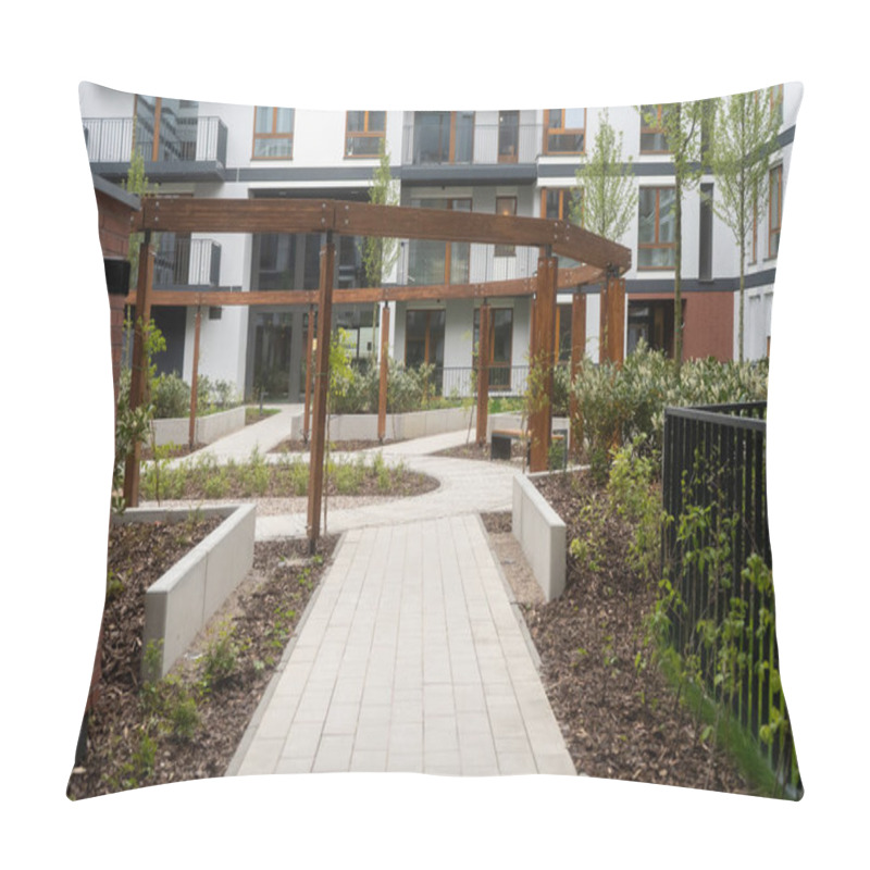 Personality  A Modern Residential Courtyard Featuring A Wooden Pergola, Landscaped Gardens, And A Neatly Paved Pathway. The Contemporary Apartment Buildings In The Background Complement The Serene Outdoor Space. Pillow Covers