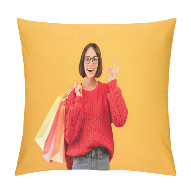 Personality  Big Sales. Excited Woman Holding Shopping Bags And Showing Ok Sign, Wearing Knitted Sweater Over Yellow Background Pillow Covers