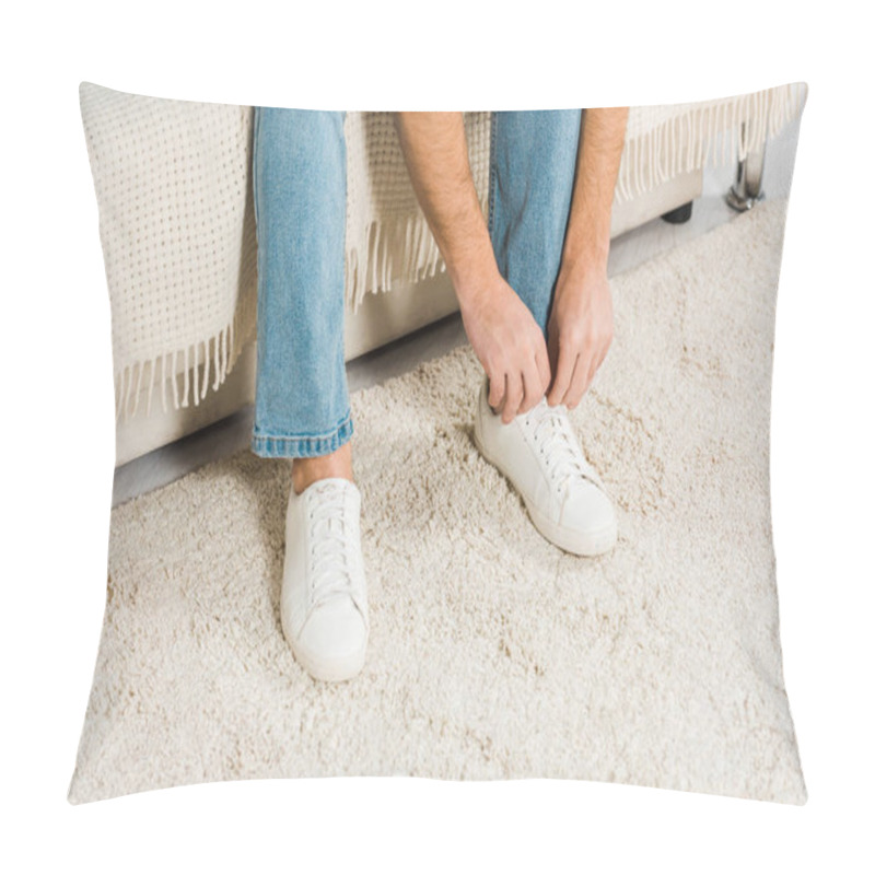 Personality  Cropped View Of Man In Jeans Sitting And Tying Shoelaces On Sneakers At Home Pillow Covers