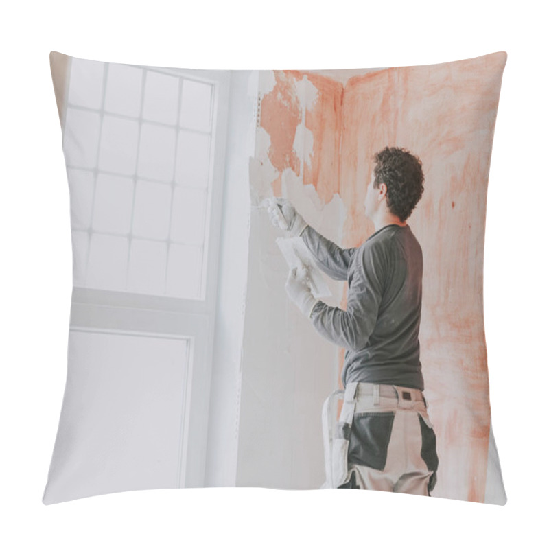 Personality  A Young Caucasian Guy In A Gray T-shirt With Sleeves, Work Pants And Curly Brown Hair Applies Fresh Putty With A Small Spatula On The Wall Near The Window, Standing On A Stepladder, Close-up Side View. The Concept Of Apartment And House Renovation, W Pillow Covers